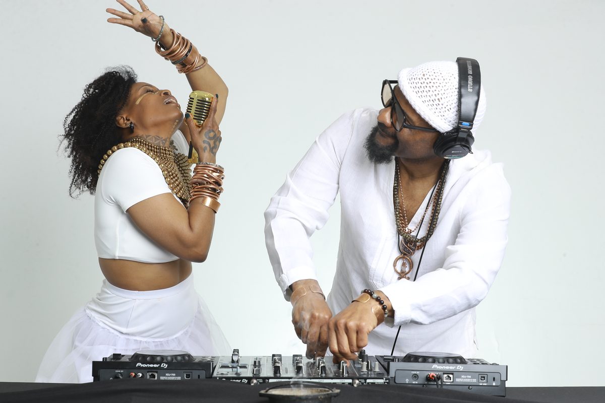 Galactic Soul Synergy — Q (QUANTUM) singing into a gold microphone beside DJ ChiProfess at the decks